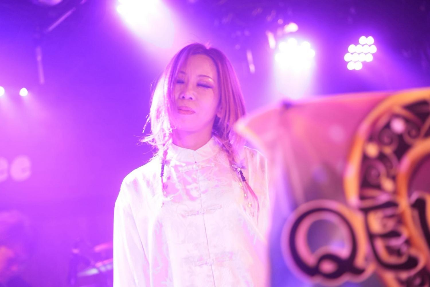 紫のスモークの中、QEUSIC旗の横で目を閉じる JUN