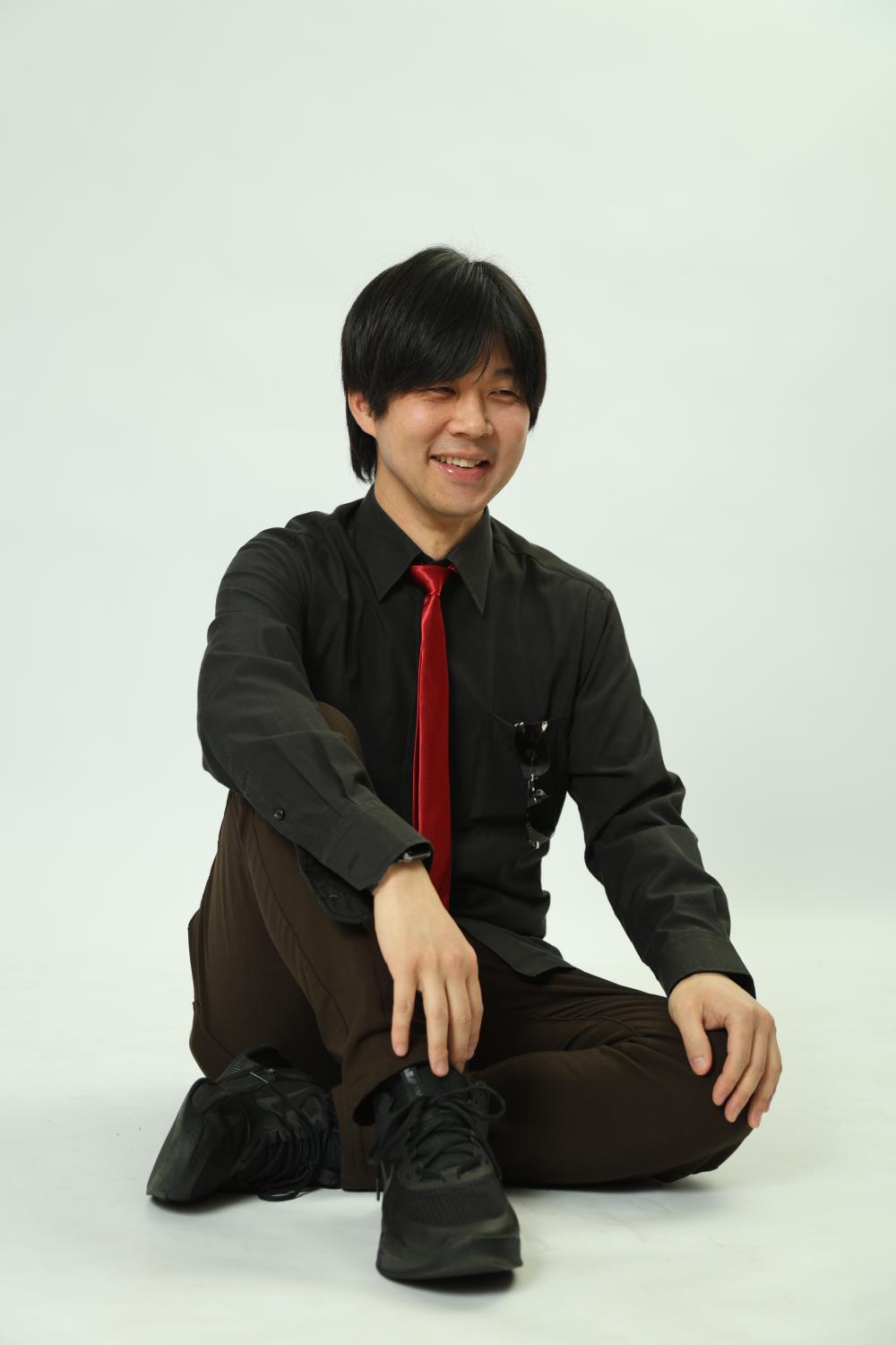 QEUSIC ギター みっくん。白い背景に座り、赤いネクタイで笑う