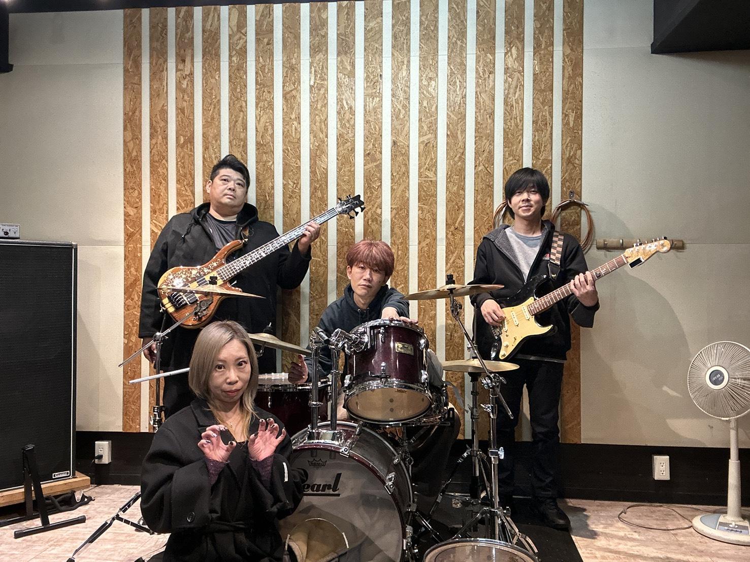 スタジオ、Pearlドラムの前。JUNが手前、のすけ・まこ・みっくんが楽器を構える