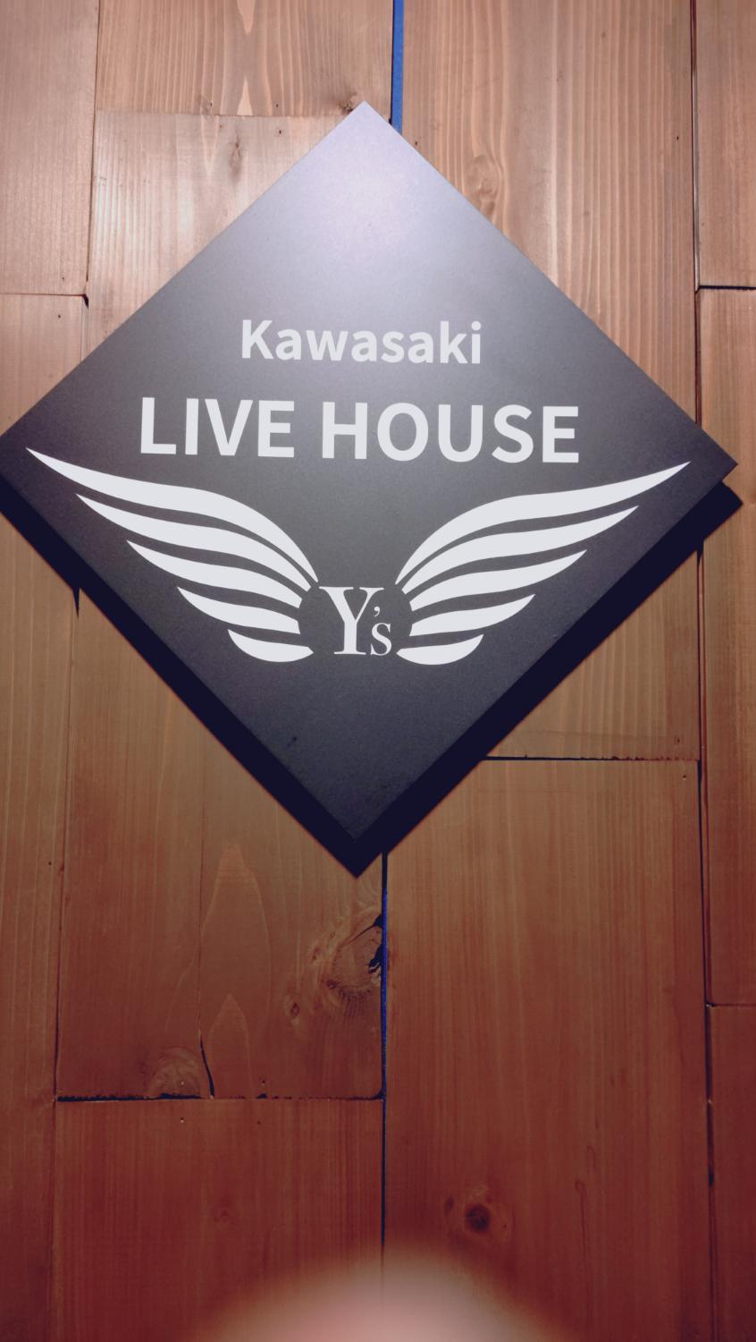 木の壁に菱形の Kawasaki LIVE HOUSE Y's 看板